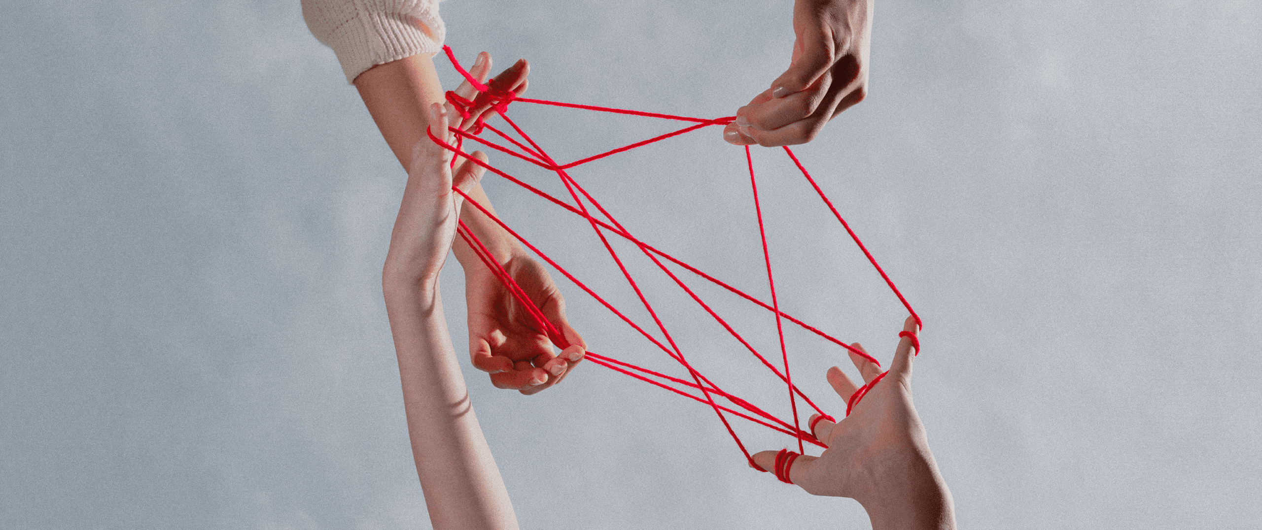 The importance of community in branding: Multiple hands connected by red strings, symbolizing community, collaboration, and interwoven brand relationships.