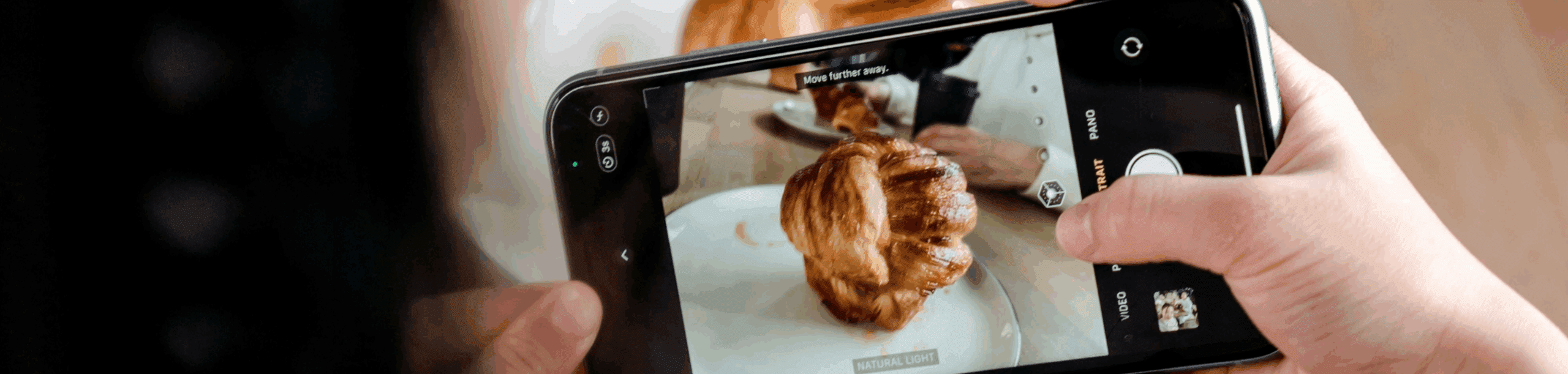Person taking a photo of a croissant with a smartphone — a typical example of user-generated content.