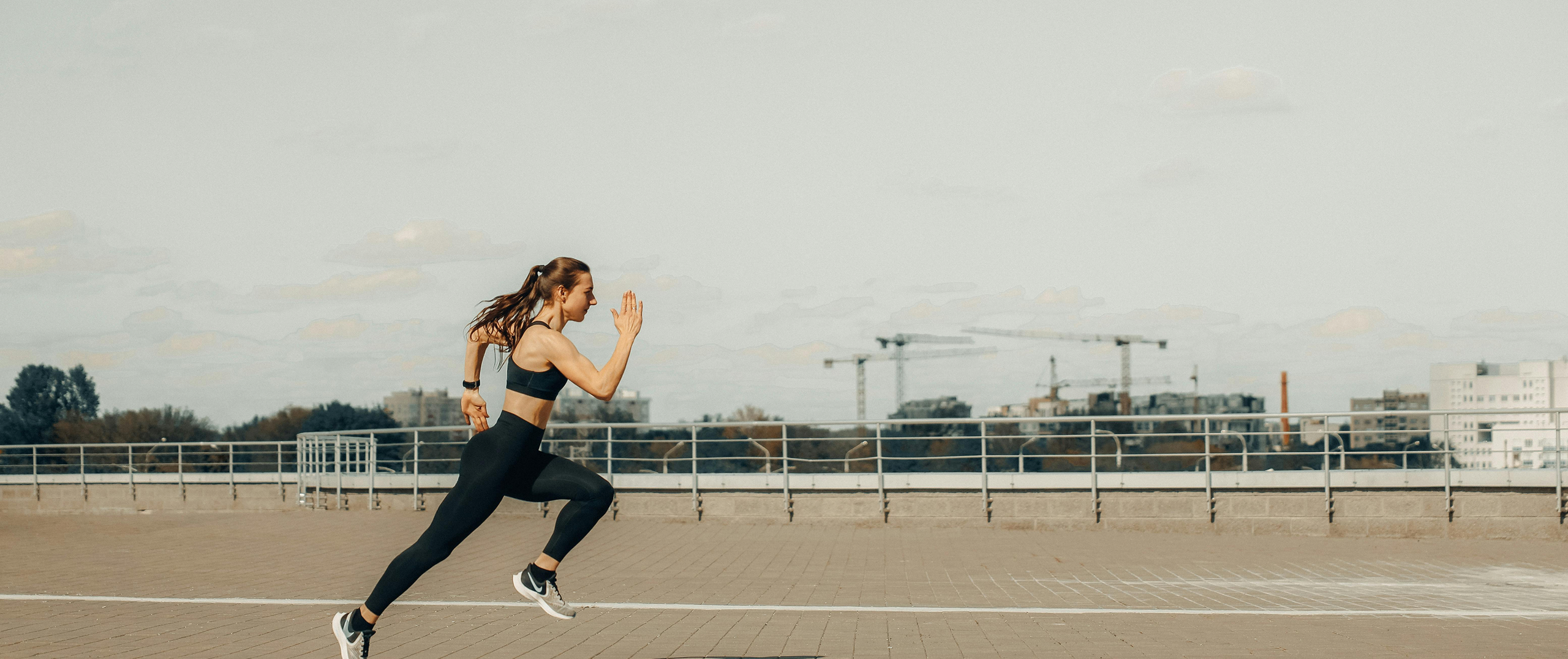 A female athlete sprinting outdoors, representing determination, performance, and the spirit of community-driven fitness.