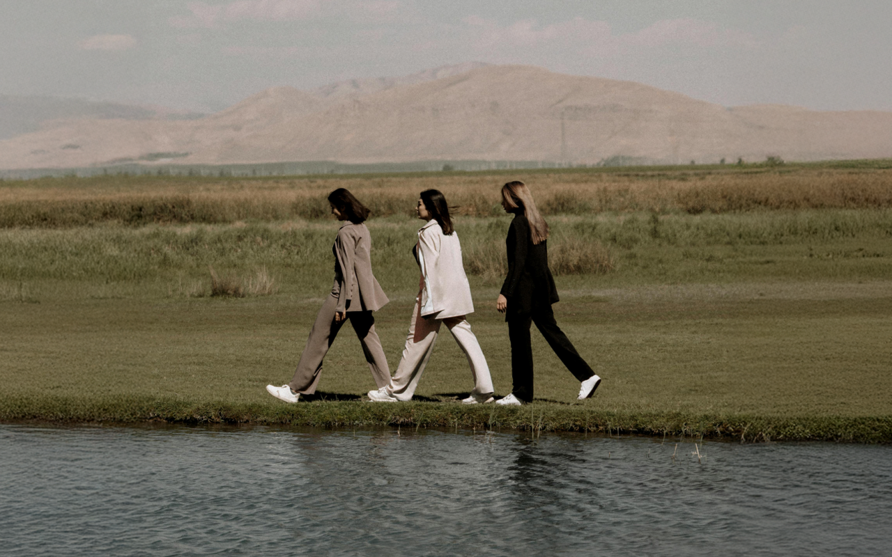 Three people walking by a lake, representing connection, unity, and the spirit of community.