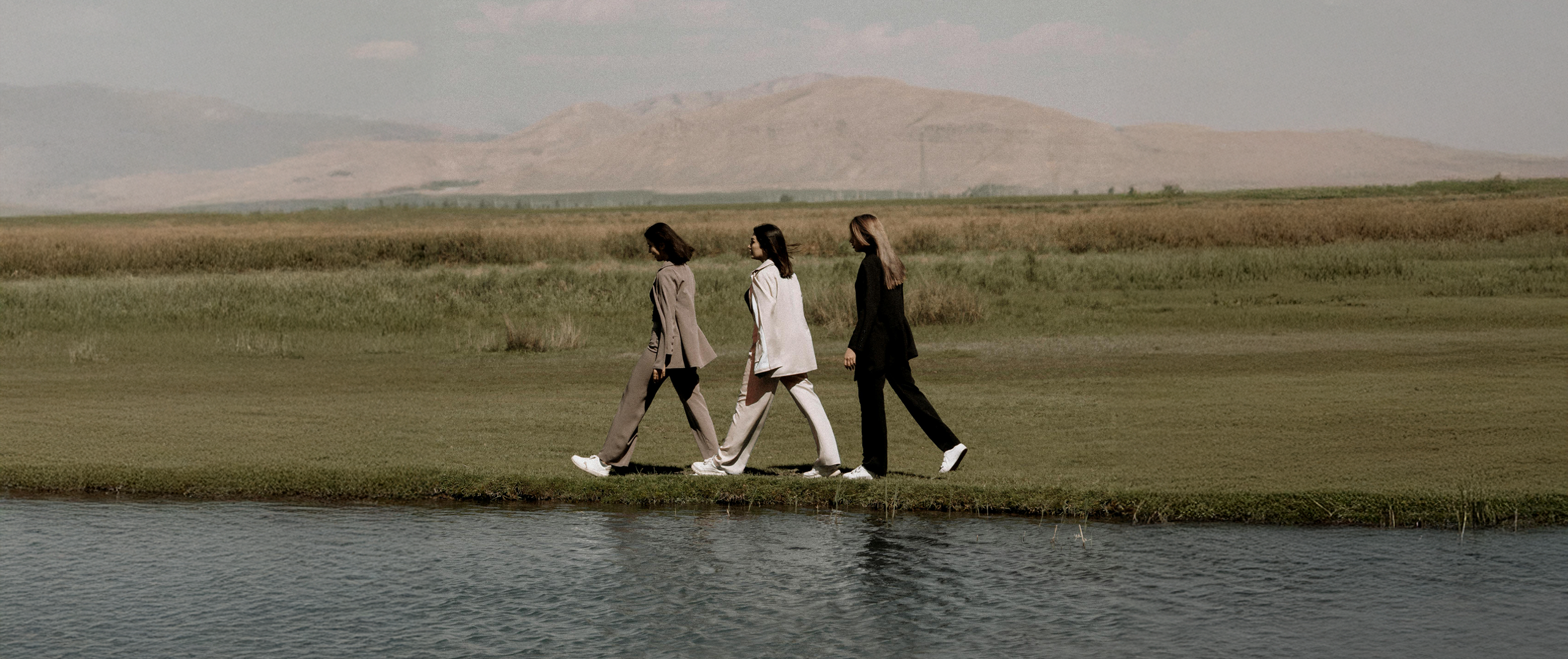 Three people walking by a lake, representing connection, unity, and the spirit of community.
