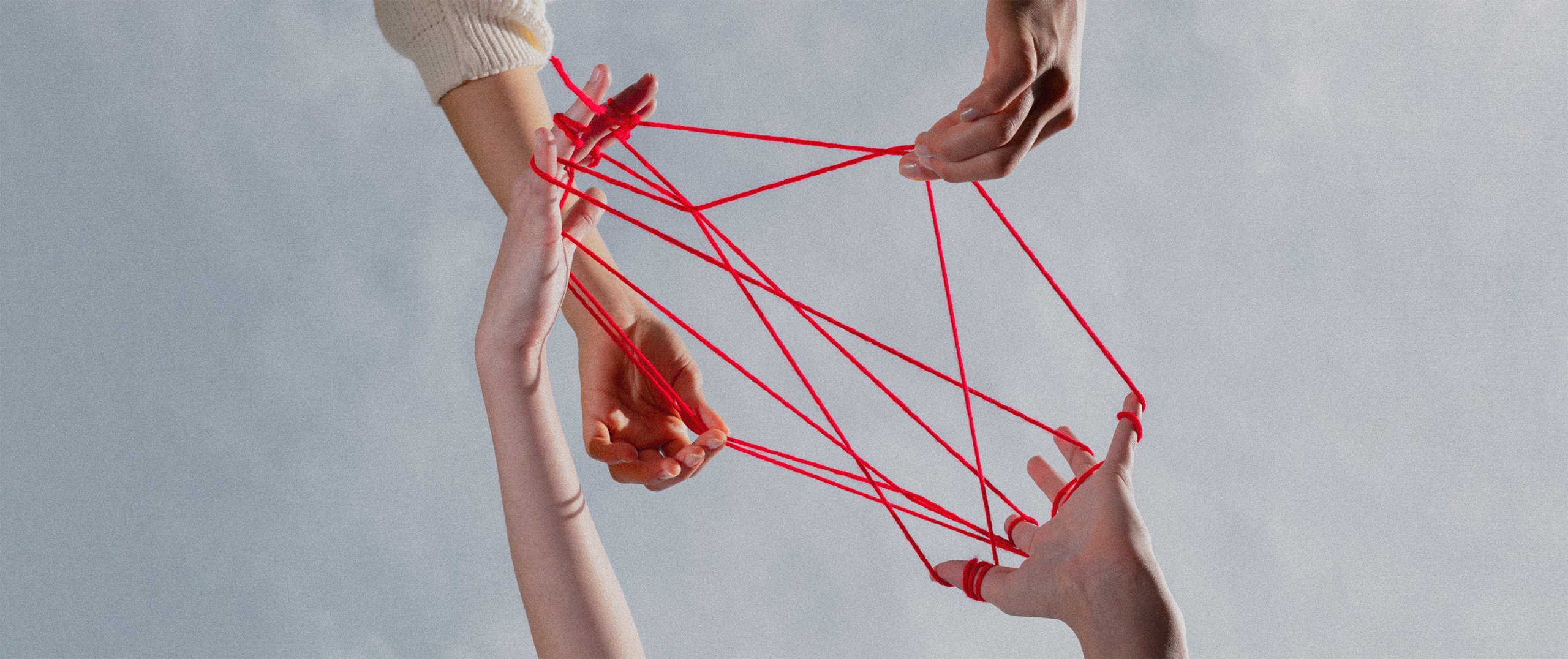 The importance of community in branding: Multiple hands connected by red strings, symbolizing community, collaboration, and interwoven brand relationships.