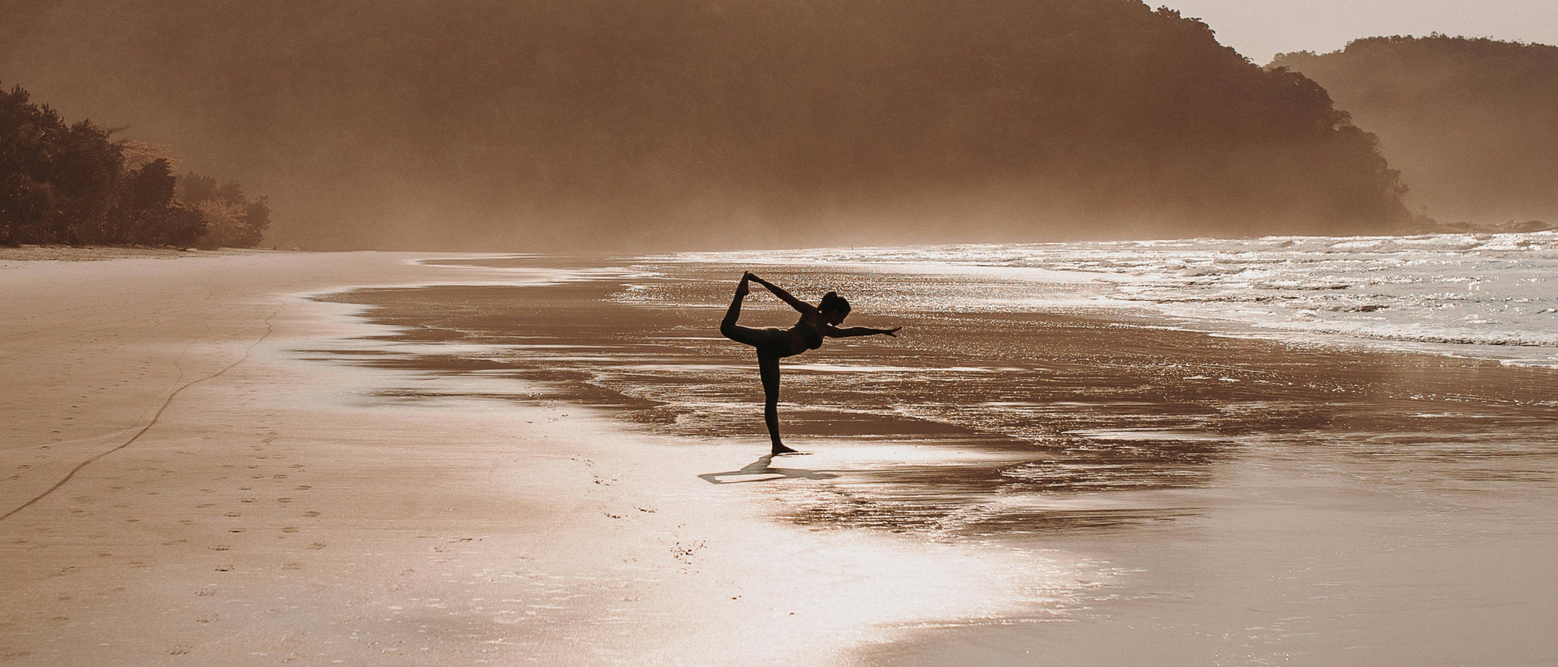 Person practicing yoga pose on a serene beach, embodying balance, resilience, and a growth mindset.